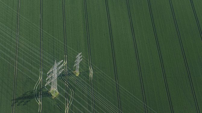 Aerial view of power poles on green field